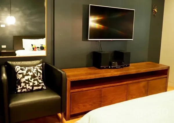 คอนโด ให้เช่าในWatthana, Bangkok - ผนังมัลติมีเดียในห้องนอนพร้อมทีวีติดผนัง ตู้คอนโซลไม้ยาว และเก้าอี้หนัง