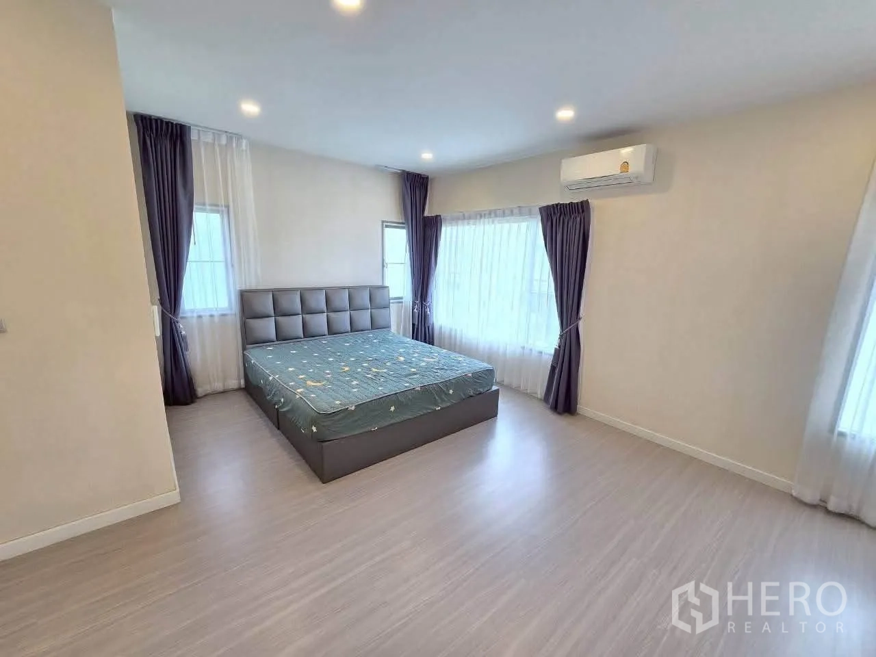 Detached House for rent or sale in Lat Krabang, Bangkok - Master bedroom with large corner windows, curtains, and air conditioner.