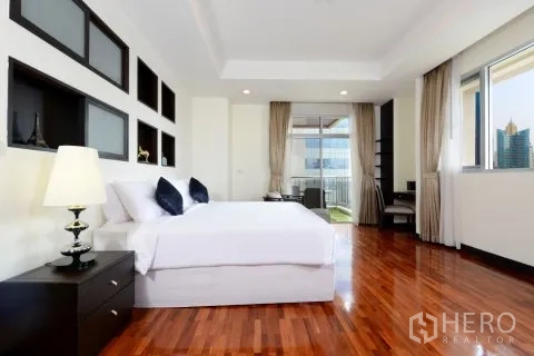 Apartment for rent in Watthana, Bangkok - Spacious bedroom with shelving features, balcony door, and natural light.