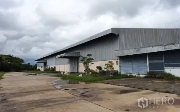 คลังสินค้า ให้เช่าในChaloem Phra Kiat, Nakhon Ratchasima - อาคารโกดังโลหะขนาดใหญ่ หลังคาที่ยาว พื้นคอนกรีตกว้างและท่าโหลด ใต้ท้องฟ้าครึ้ม