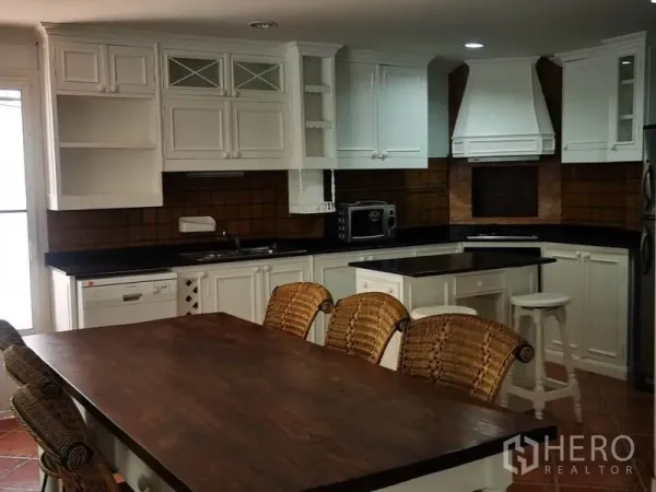 独立式住宅 出租在Mueang Samut Prakan, Samut Prakan - 乡村风白色橱柜厨房，带中岛和长木餐桌藤椅