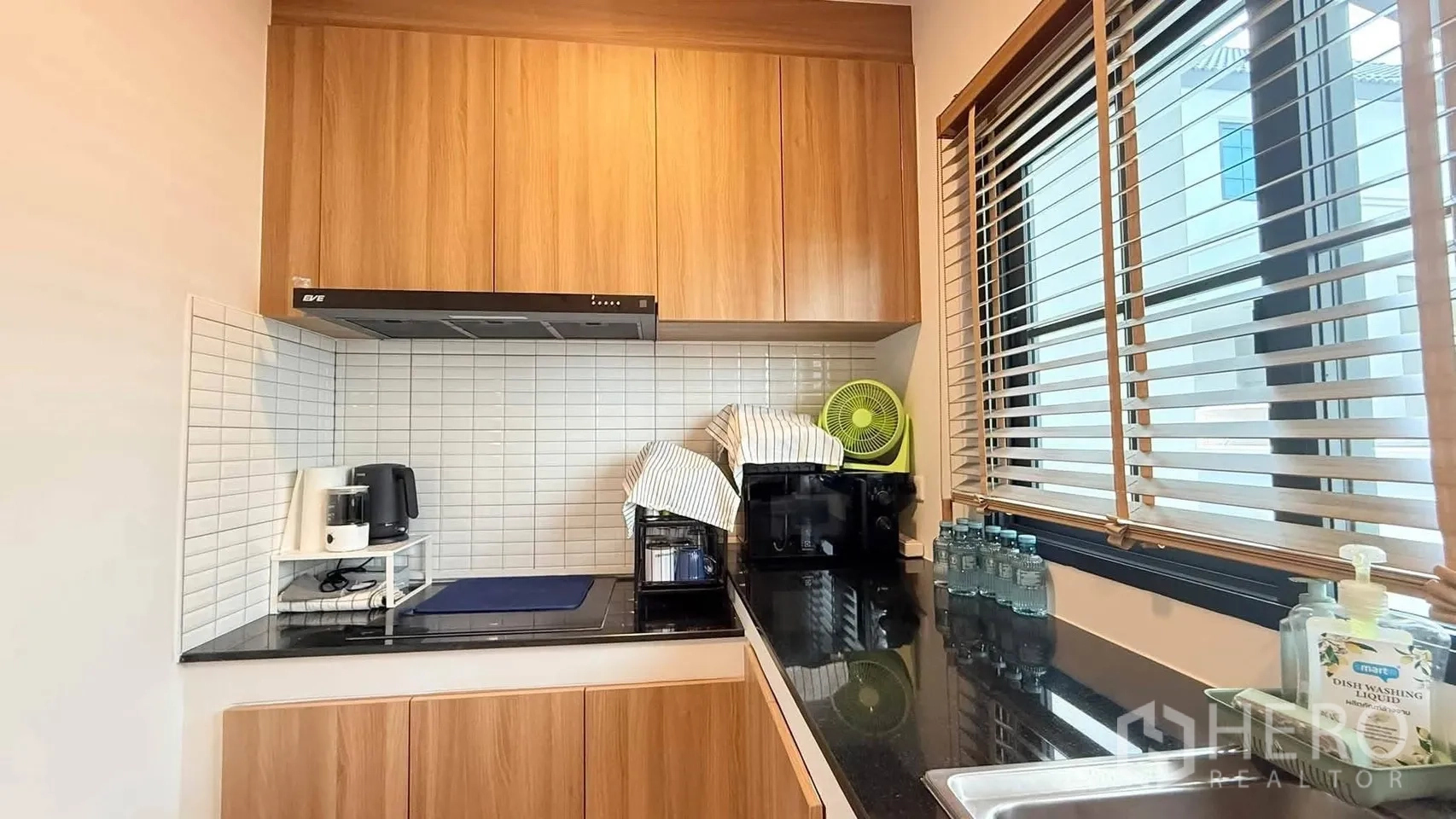 独栋房屋 for rent in Bang Phli, Samut Prakan - 紧凑厨房，木色橱柜、黑色花岗岩台面、白色瓷砖防溅板与百叶窗。