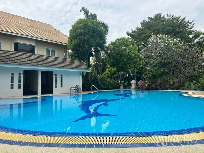 Detached House for sale in Suan Luang, Bangkok - Community swimming pool and clubhouse surrounded by tropical trees.