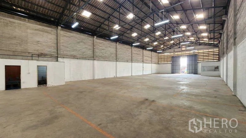 Warehouse for rent in Khlong Toei, Bangkok - Wide warehouse hall facing the entrance, marked loading bays and metal roof structure visible.