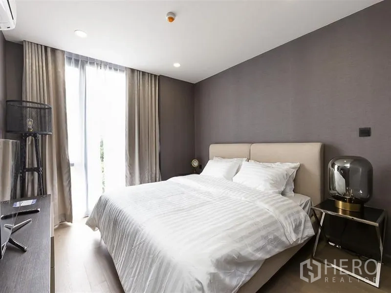 คอนโด ให้เช่าในPathum Wan, Bangkok - ห้องนอนหลักเตียงบุนวม แสงนุ่มนวล และหน้าต่างสูงจรดเพดาน