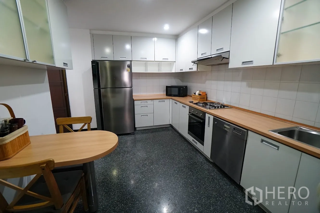 房间 出租在Watthana, Bangkok - 明亮厨房，大量柜体、早餐角与大冰箱。