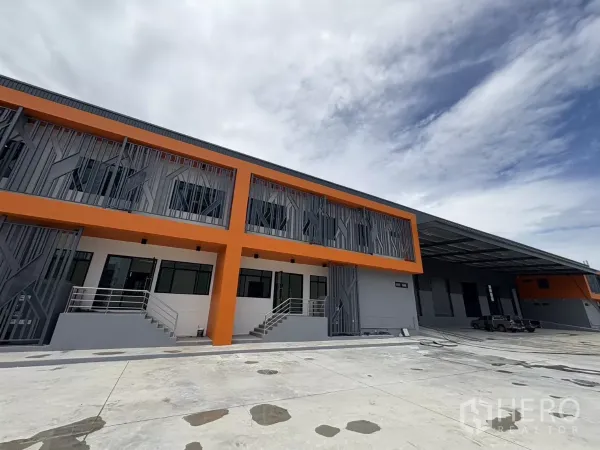 工厂 出租在Bang Pakong, Chachoengsao - 工厂正面广角视图，带有遮棚装卸区和宽阔混凝土场地