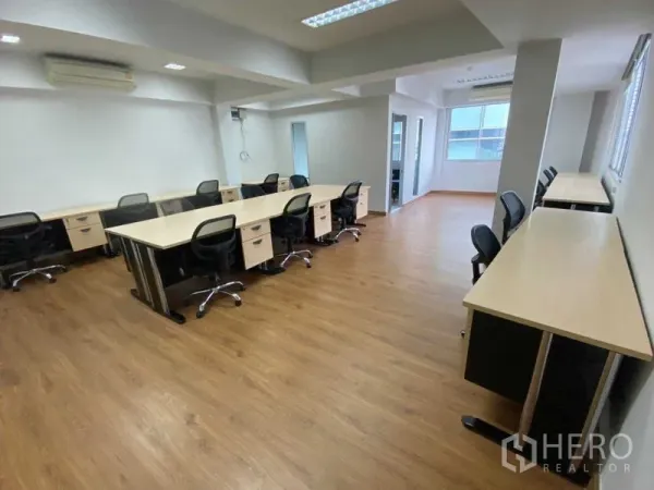 Office Space for rent in Khlong Toei, Bangkok - Spacious workspace with multiple desks, windows, ceiling lights, and warm timber-style flooring.