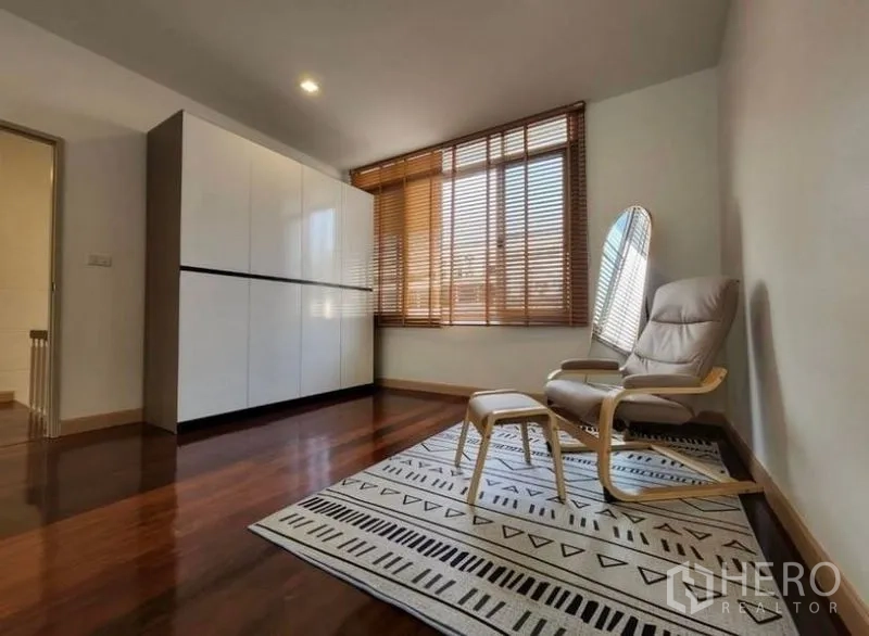 Townhouse for sale - Second bedroom or reading nook with wardrobe, lounge chair and wood blinds.