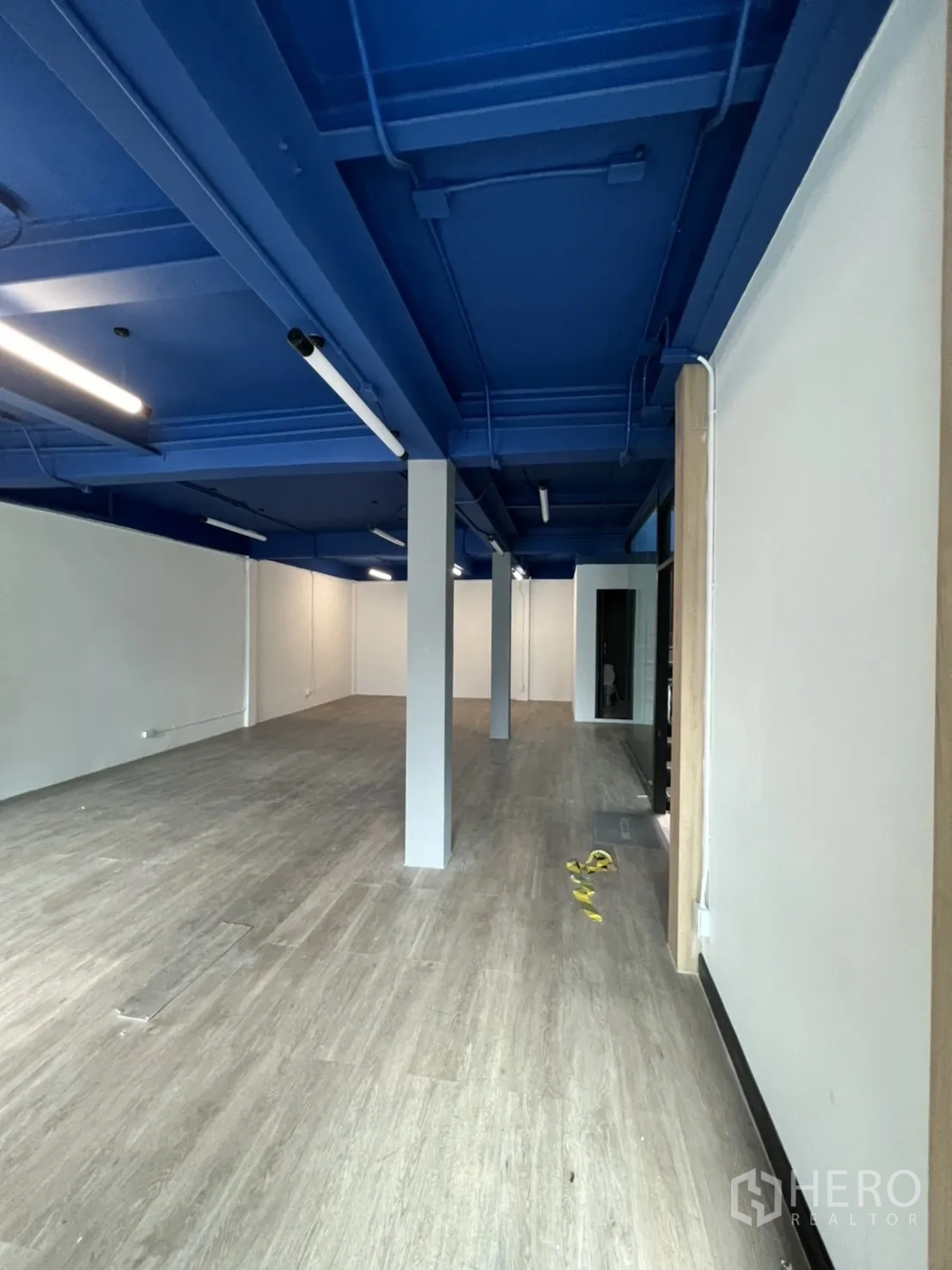 สำนักงาน ให้เช่าในWatthana, Bangkok - ทางเดินสำนักงานกว้าง มีเสากลาง เพดานสีน้ำเงินสไตล์อินดัสเทรียล และพื้นไวนิล