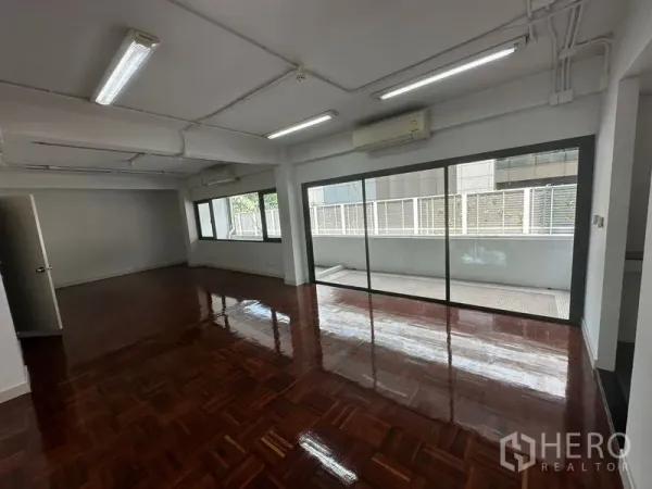 办公空间 出租 - 宽敞的开放式办公室，亮面拼花木地板，推拉玻璃门通往阳台。