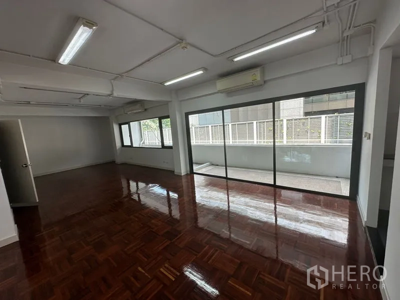 办公空间 出租 - 宽敞的开放式办公室，亮面拼花木地板，推拉玻璃门通往阳台。