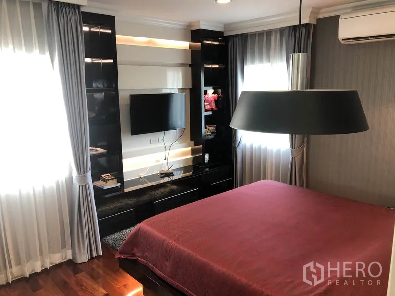 Detached House for rent or sale in Saphan Sung, Bangkok - Cozy bedroom with feature lighting, wall-mounted TV, and large windows.