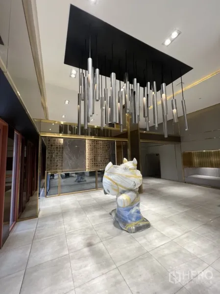 店屋 出租在Phra Khanong, Bangkok - 开放式展厅，吊灯装置感强，整片瓷砖地与玻璃立面。