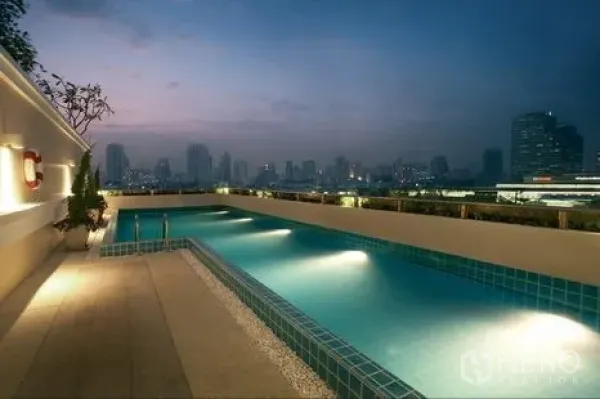 Condominium for rent or sale in Khlong Toei, Bangkok - Rooftop swimming pool at dusk with Bangkok skyline and underwater lights.