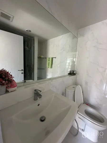 คอนโด ขายในKhlong Toei, Bangkok - ห้องน้ำผนังลายหินอ่อน พร้อมอ่างล้างหน้า กระจกบานใหญ่ และโถสุขภัณฑ์