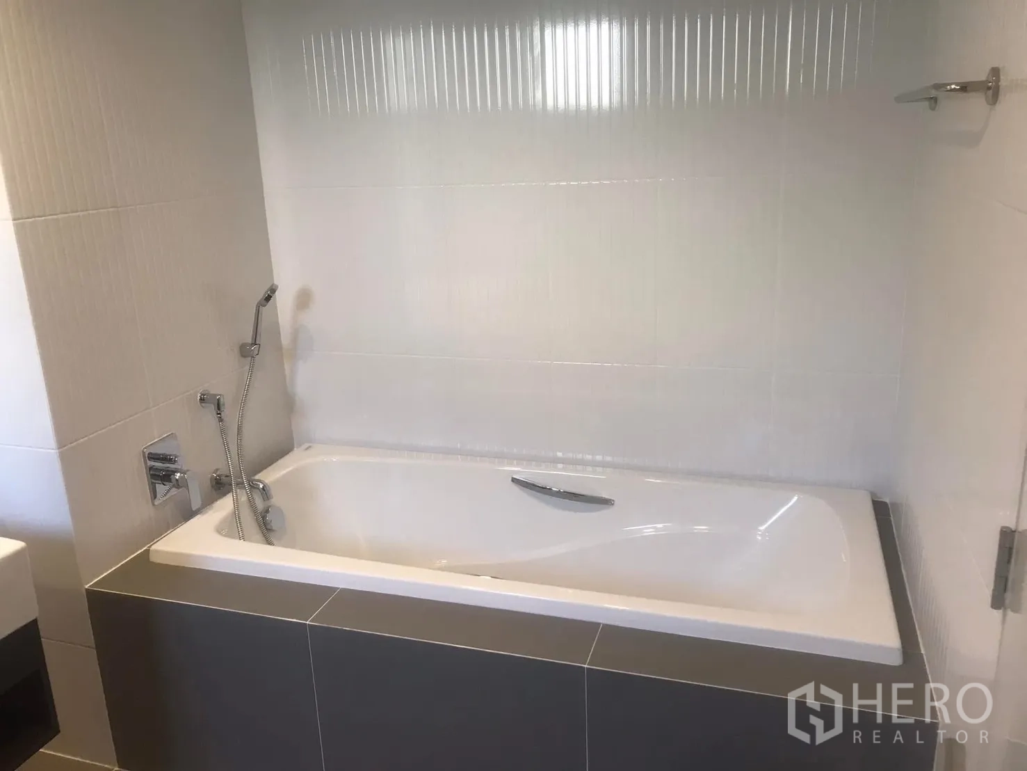 Semi-detached House for rent in Saphan Sung, Bangkok - Bathroom with built-in bathtub and handheld shower against light-tiled walls.