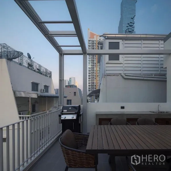 Detached House for rent in Bang Rak, Bangkok - Rooftop BBQ area with dining table and railings between neighboring buildings.