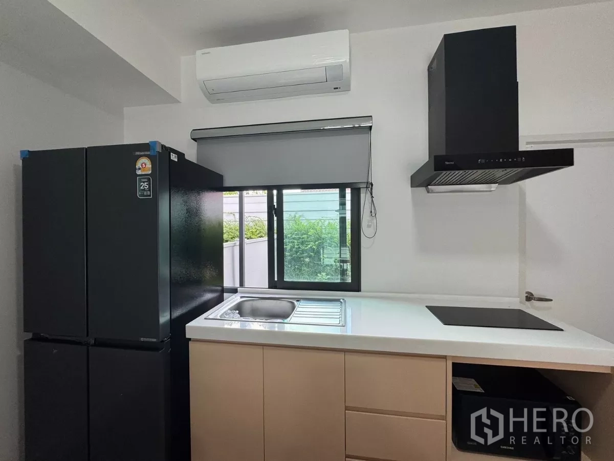 Townhouse for rent in Bang Phli, Samut Prakan - Close-up of sink, induction cooktop, range hood, and garden view window