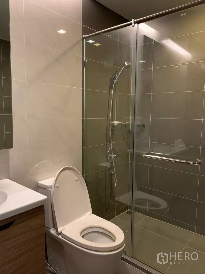 Condominium for rent or sale in Watthana, Bangkok - Contemporary bathroom with glass-enclosed shower, vanity and toilet.