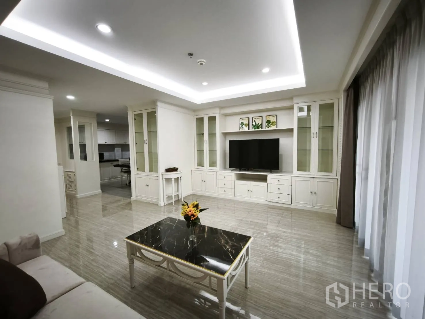 Condominium for rent in Watthana, Bangkok - Open-plan living and dining area connecting to the kitchen with built-in shelving and glossy floors.