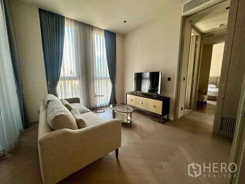 公寓 出租 - 采光良好的客厅，米色沙发、电视柜与落地窗帘