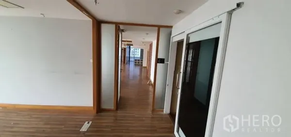 Office Space for rent in Watthana, Bangkok - Hallway with a sliding glass door and wooden trims opening into a partitioned office zone.