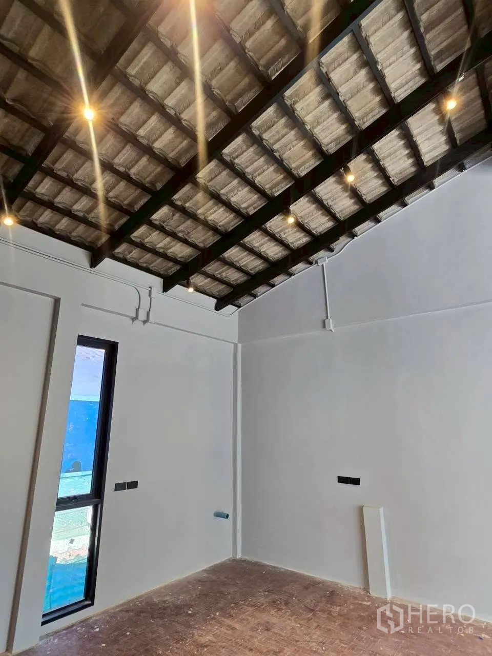 Detached House for rent in Phra Khanong, Bangkok - Upper room with insulated sloped ceiling, spotlights, and narrow window.