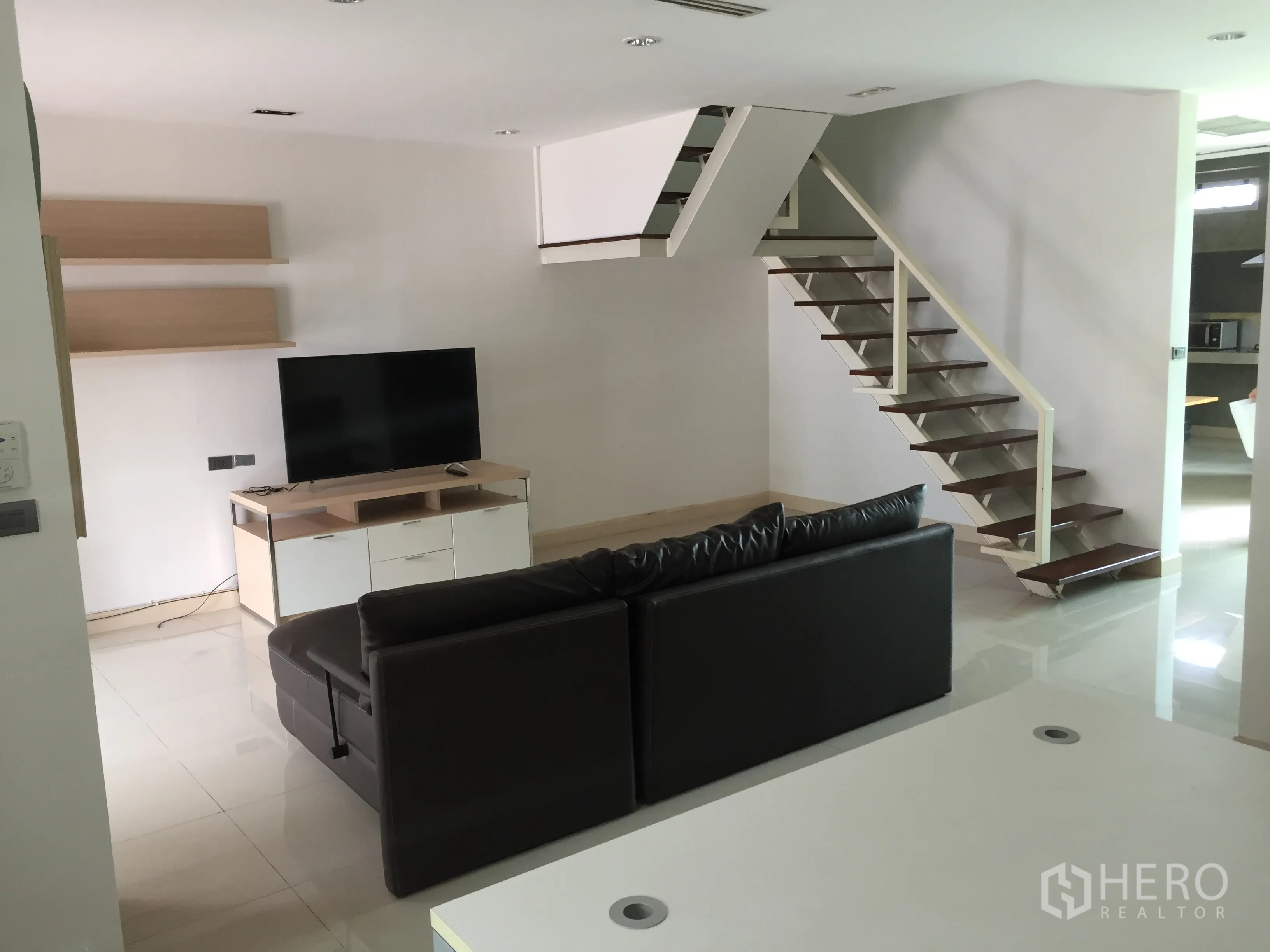 ทาวน์เฮาส์ ให้เช่าในDin Daeng, Bangkok - มุมมองอีกด้านของห้องนั่งเล่น โชว์ทีวี ชั้นวาง และบันไดขึ้นชั้นบน