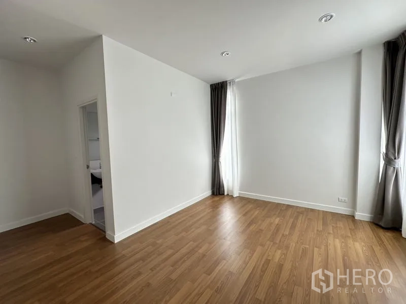 บ้าน ขายในLam Luk Ka, Pathum Thani - ห้องนอนอีกห้อง พื้นไม้ ผ้าม่าน และประตูเข้าห้องน้ำ