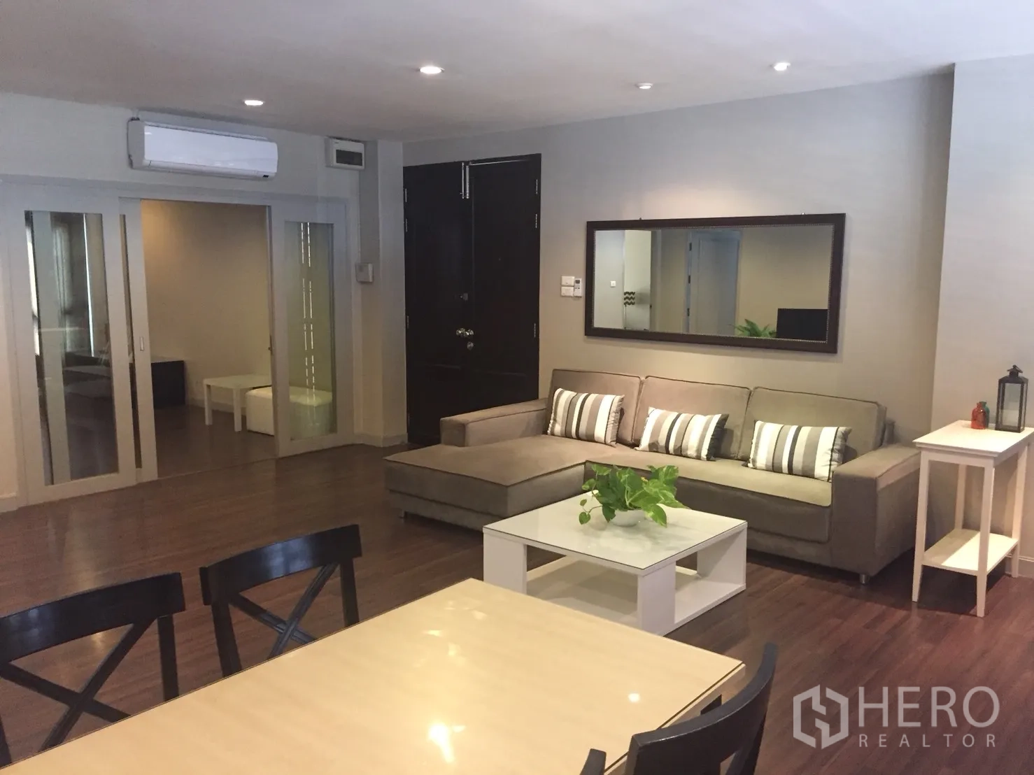 อพาร์ทเมนท์ ให้เช่าในKhlong Toei, Bangkok - พื้นที่นั่งเล่นและทานอาหารแบบเปิดโล่ง มีประตูบานเลื่อนกระจก ไฟดาวน์ไลท์ และพื้นไม้