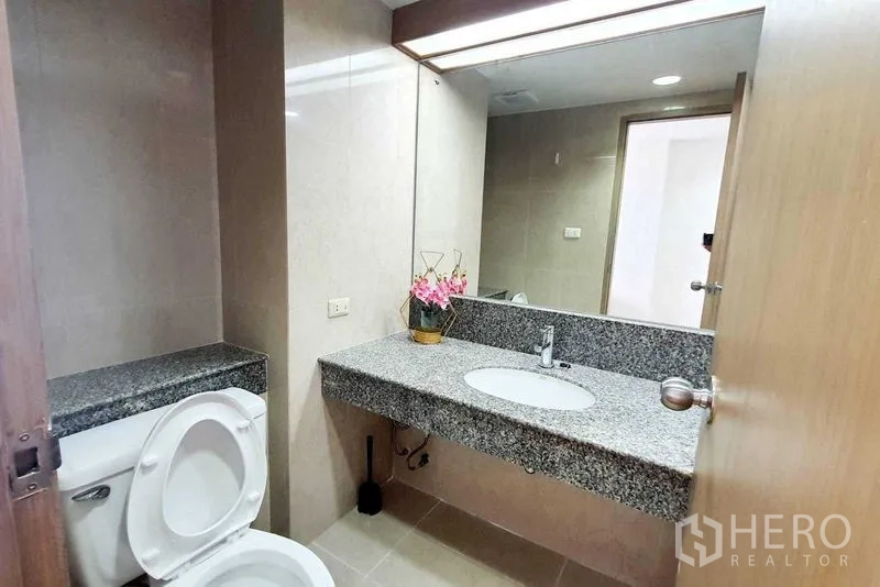 Condominium for sale in Bang Kho Laem, Bangkok - Second bathroom with long granite countertop, large mirror and toilet.