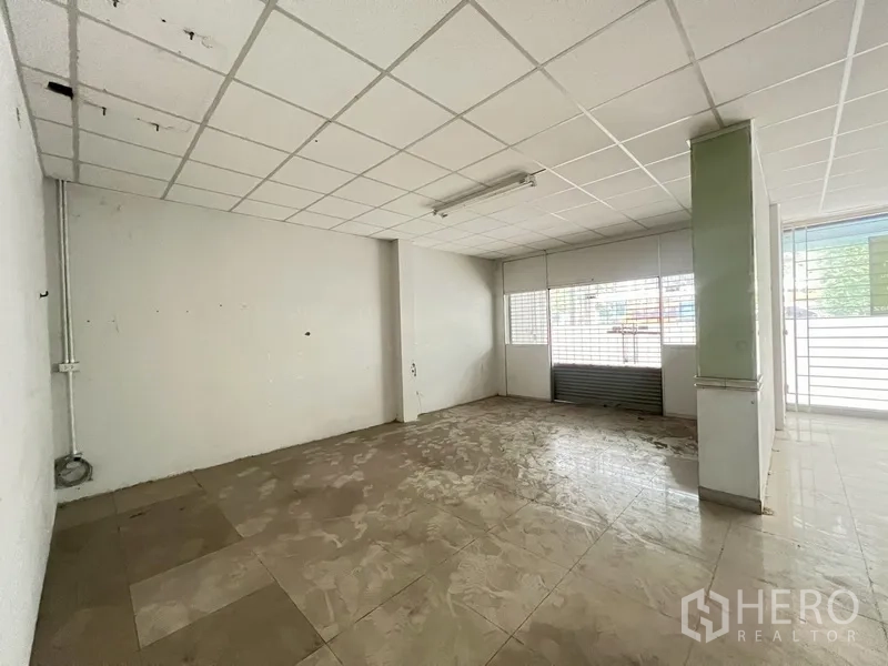 店屋 出租在Phra Khanong, Bangkok - 一层前厅，卷闸门口，地砖与立柱。