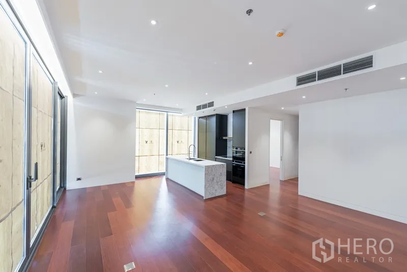 คอนโด ขายในWatthana, Bangkok - มองข้ามพื้นที่นั่งเล่นไปยังครัวสมัยใหม่พร้อมไอส์แลนด์หินอ่อน เตาอบบิวท์อิน และตู้สูง