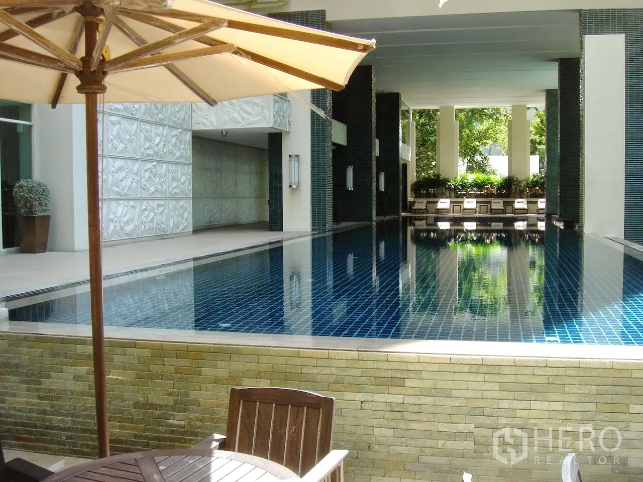 คอนโด ให้เช่าหรือขายในPathum Wan, Bangkok - ส่วนกลางคอนโดที่มีสระว่ายน้ำแบบครึ่งในร่ม พร้อมเตียงอาบแดดและพื้นที่สีเขียว