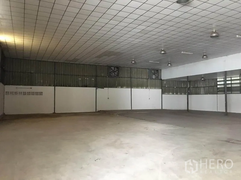 货栈 出租在Prawet, Bangkok - 宽大的储存大厅，吸音板天花、吊灯与侧墙通风窗。