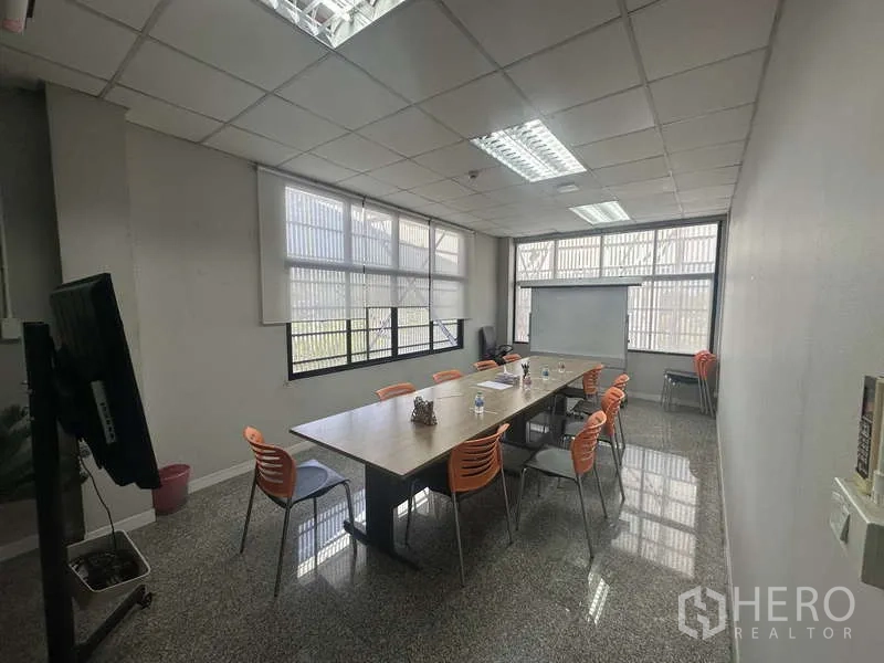 Warehouse for rent in Khlong Sam Wa, Bangkok - Meeting room with long table, orange chairs, TV screen and whiteboard.