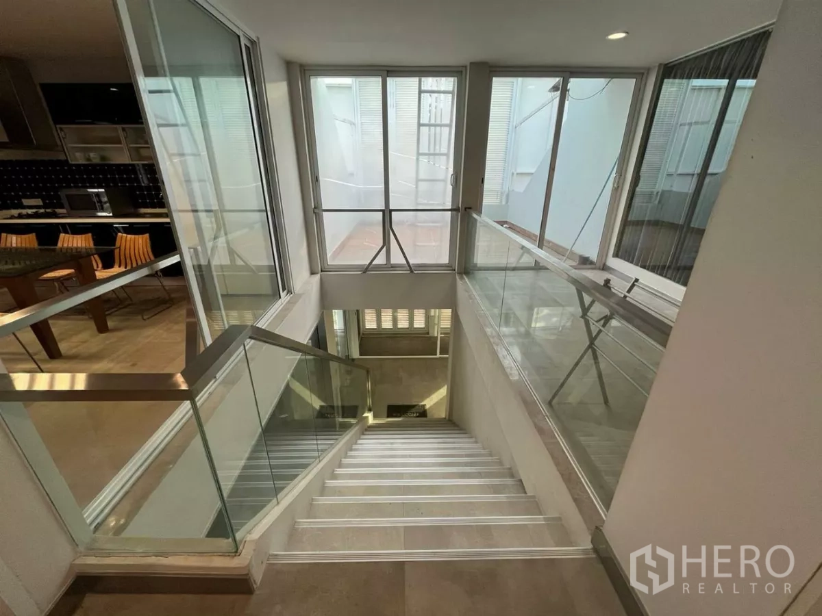Home Office for rent in Khlong Toei, Bangkok - Staircase with stainless steel and tempered-glass railings beside the kitchen area.