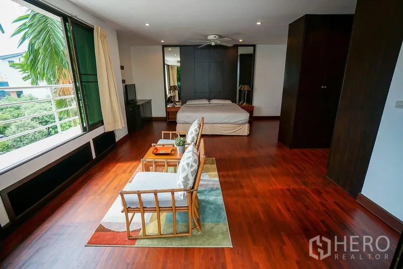 อพาร์ทเมนท์ ให้เช่าในWatthana, Bangkok - ห้องนอนมาสเตอร์กว้าง พื้นไม้ มีมุมนั่งเล่นและหน้าต่างบานกว้างมองเห็นต้นไม้