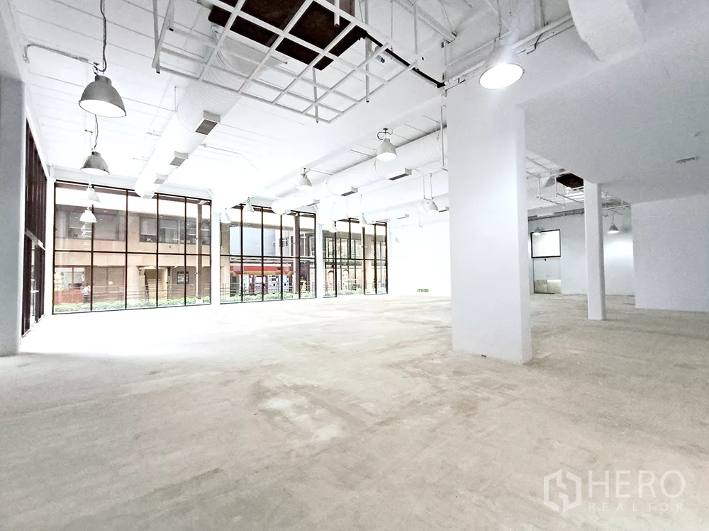 Office Space for rent in Watthana, Bangkok - Corner view of expansive workspace showing grid ceiling detail and tall windows on two sides.