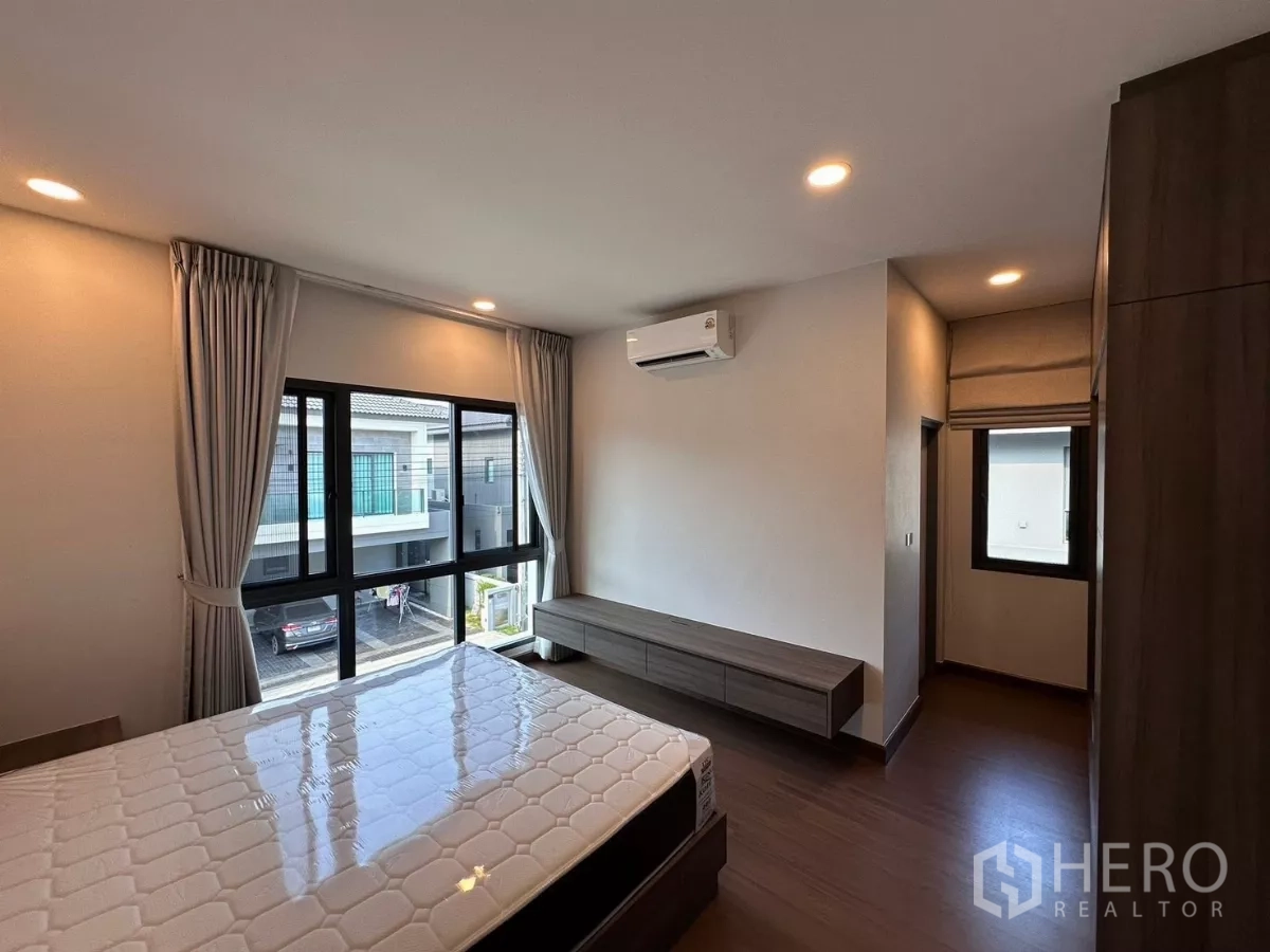 Detached House for rent in Bang Phli, Samut Prakan - Bright bedroom with large windows, air conditioner, and built-in console.