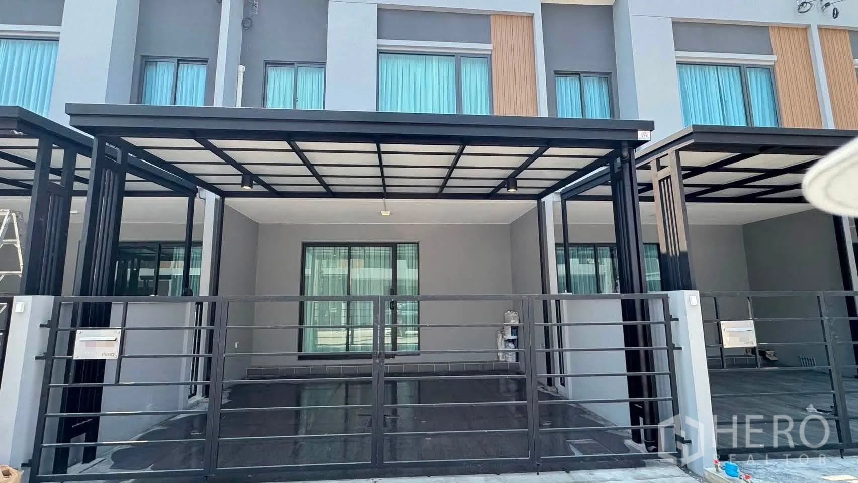 Townhouse for rent in Bang Phli, Samut Prakan - Modern townhouse exterior with gated, covered carport and sliding windows.
