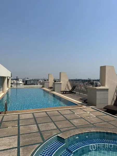 Condominium for sale in Watthana, Bangkok - Rooftop lap pool and round spa pool with wide city views and sun deck seating.