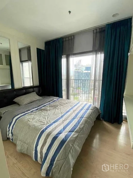 Condominium for rent in Khlong Toei, Bangkok - Cozy second bedroom with panoramic windows, dark curtains and skyline view.
