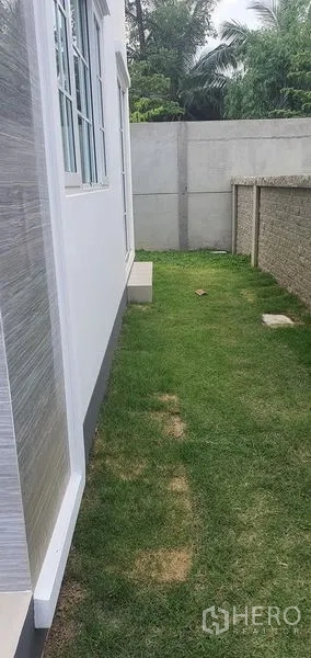 Detached House for rent in Nonthaburi - Neat side yard with green lawn and privacy wall beside the house in Pak Kret, Nonthaburi.