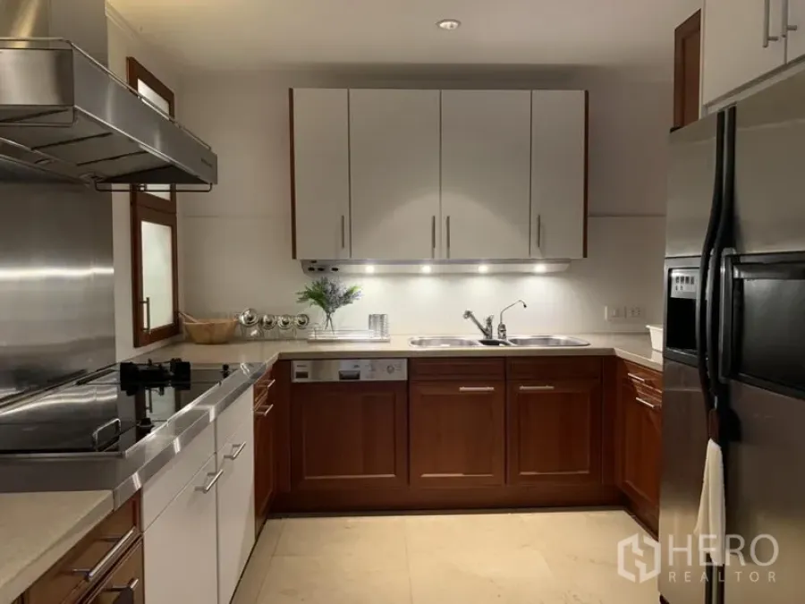 Condominium for rent or sale in Watthana, Bangkok - Modern U-shaped kitchen with wood cabinetry, stainless appliances and a double sink.