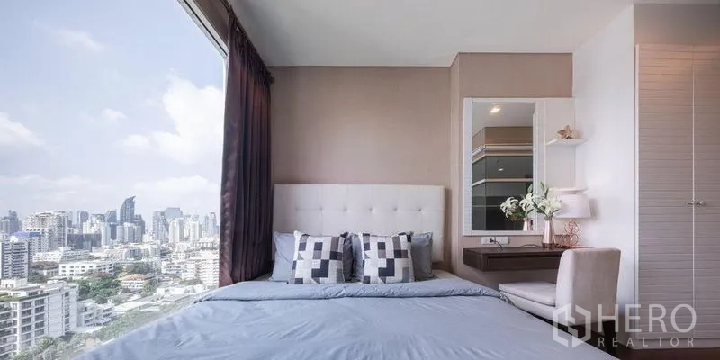 คอนโด ให้เช่าหรือขายในWatthana, Bangkok - ห้องนอนพร้อมหัวเตียงบุ โต๊ะเครื่องแป้ง และหน้าต่างบานใหญ่เห็นวิวสกายไลน์กรุงเทพฯ