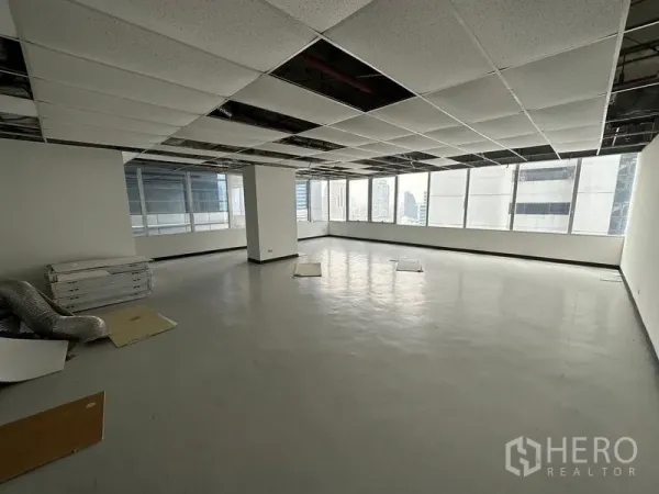 办公空间 出租在Chatuchak, Bangkok - 未配家具的开敞式办公室，部分吊顶打开，地面平整，大面积转角窗可见曼谷城市景观。