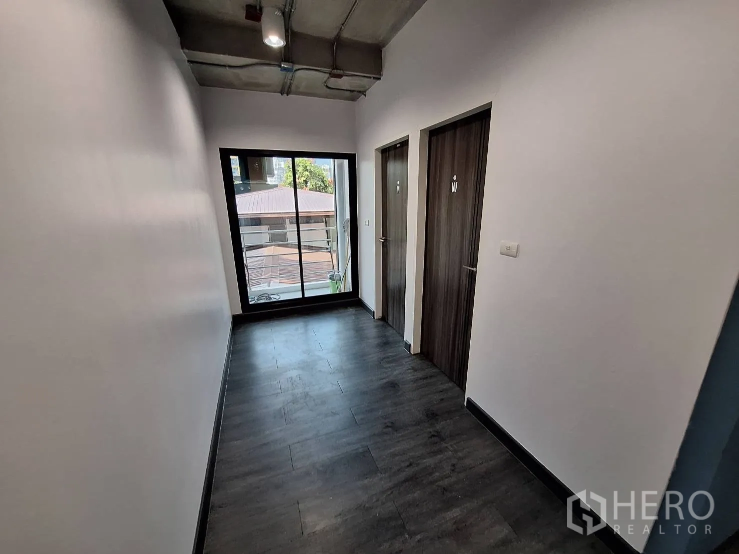 Office Space for rent - Hallway with two restroom doors and a sliding glass door to a balcony.