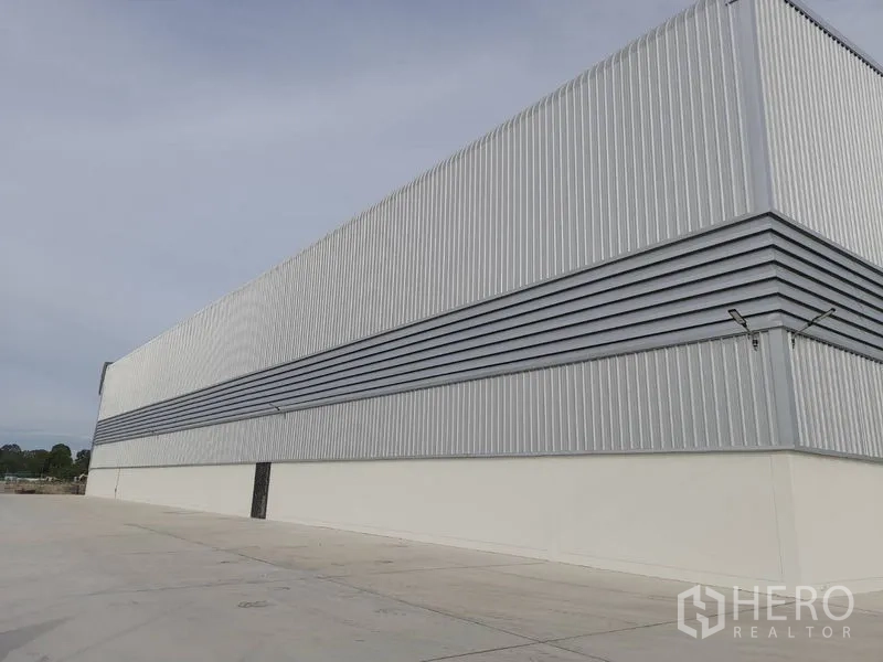 工厂 出租在Mueang Rayong, Rayong - 钢板围护的长外墙与大面积混凝土硬化场地。